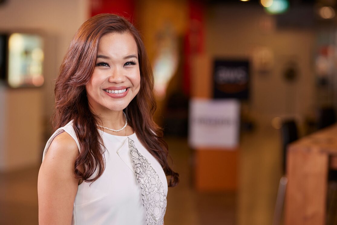 A headshot image of a woman smiling for a photo in the lobby of an Amazon office.