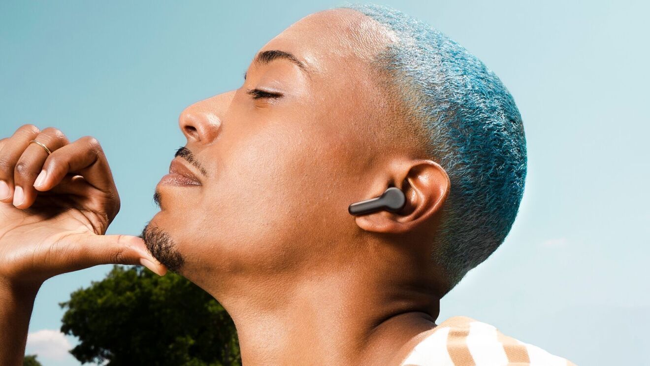 Ein Bild von Echo Buds im Ohr von Mann mit blauen Haaren.
