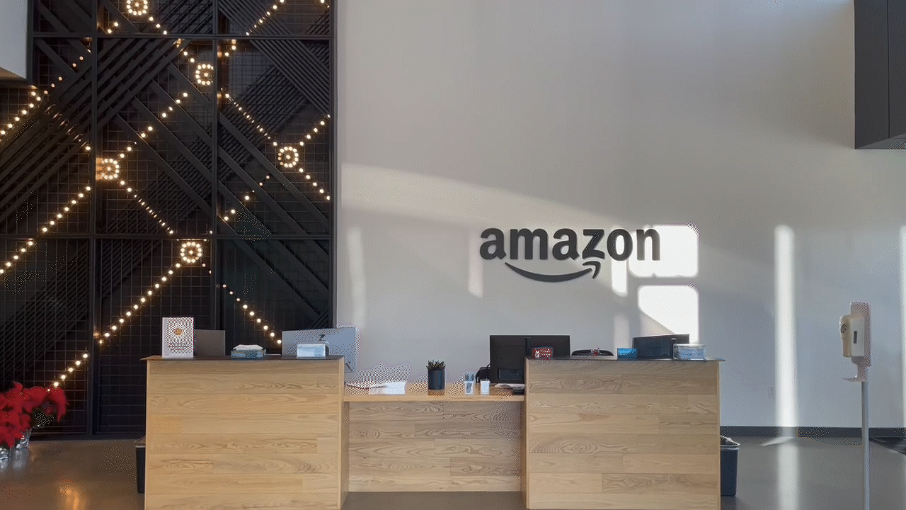 An animated GIF of the lobby of the Amazon Robotics facility where there is a black light installation behind the desk that slowly flicker yellow lights.