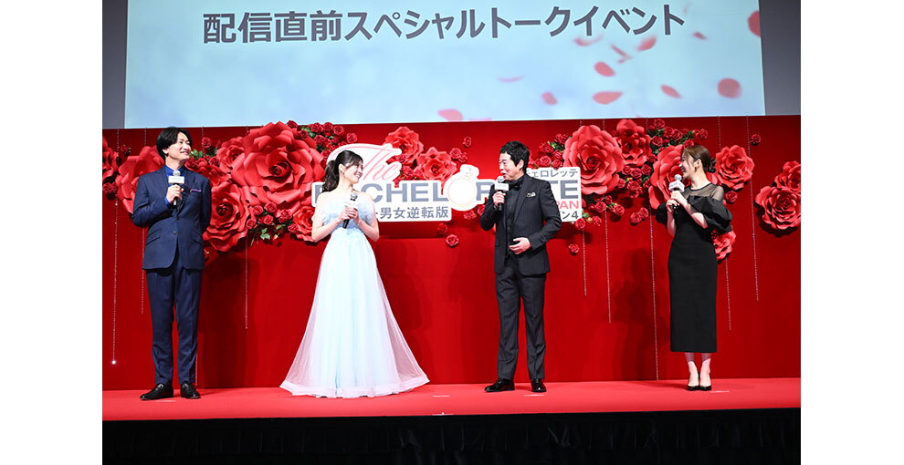 赤いバラの花の大きなオブジェと生花の赤いバラが飾られた赤い壁を背に並んで立つ4人の人物。情報のスクリーンに「配信直前スペシャルトークイベント」の文字。