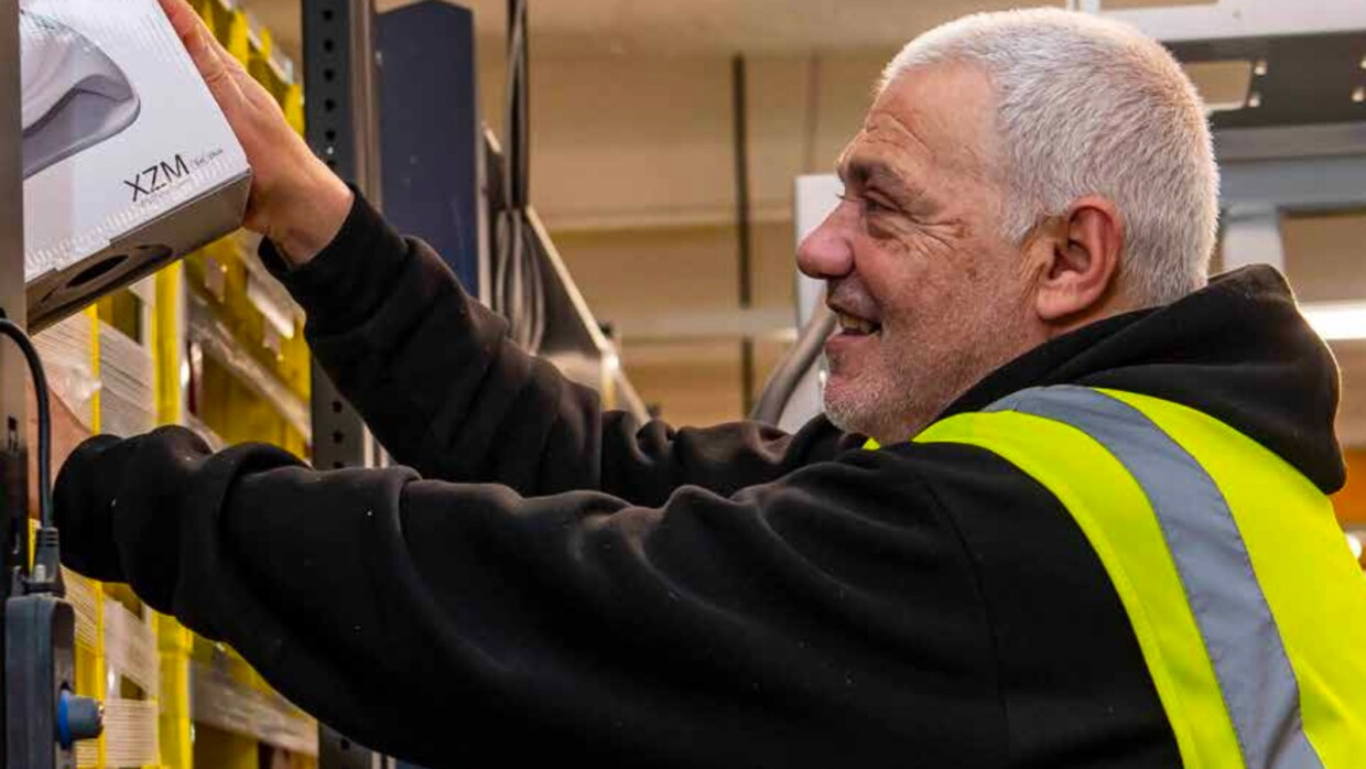 An over-55 person picking goods in an Amazon warehouse.