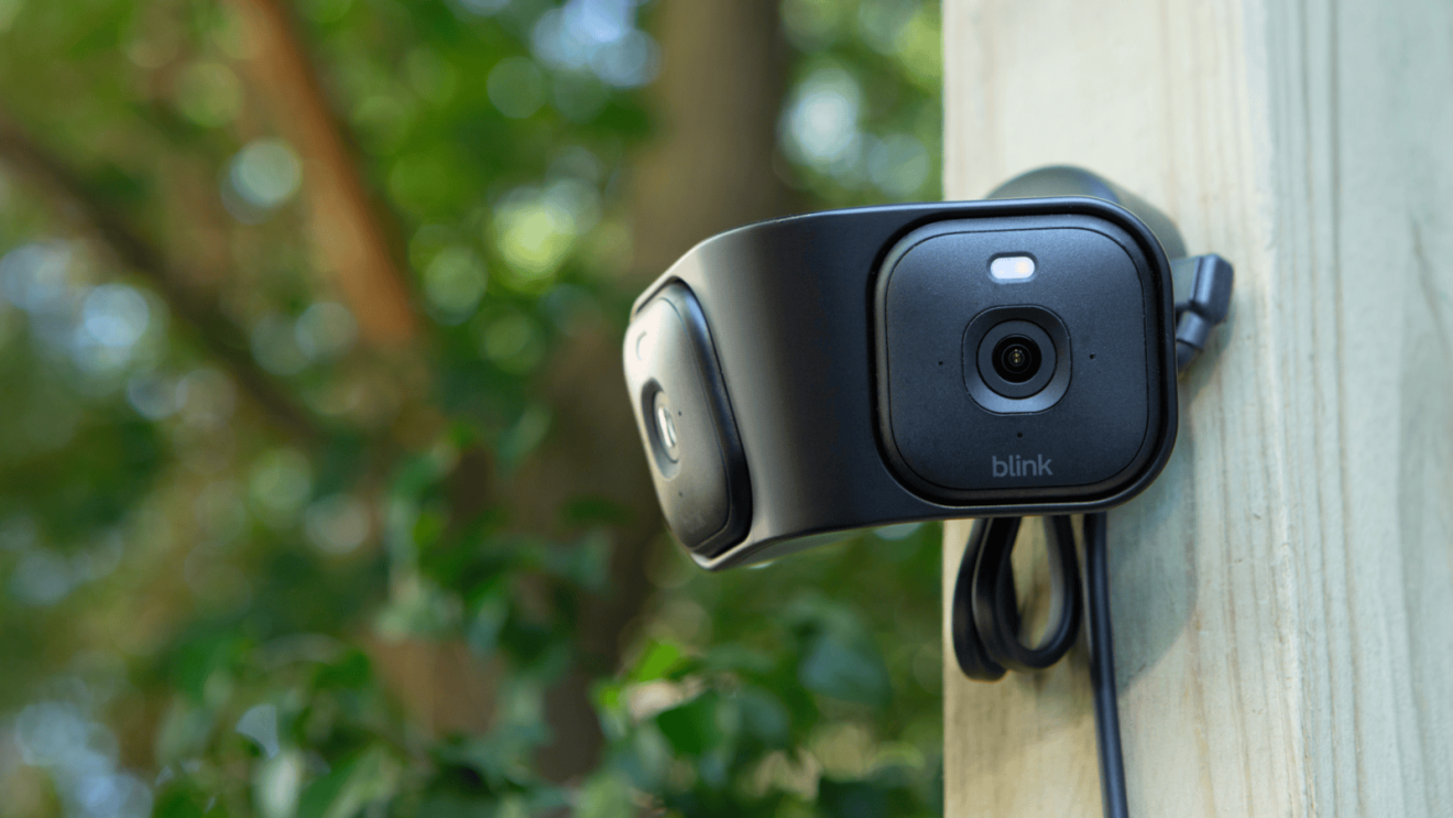 Black wireless camera installed on porch column with greenery background