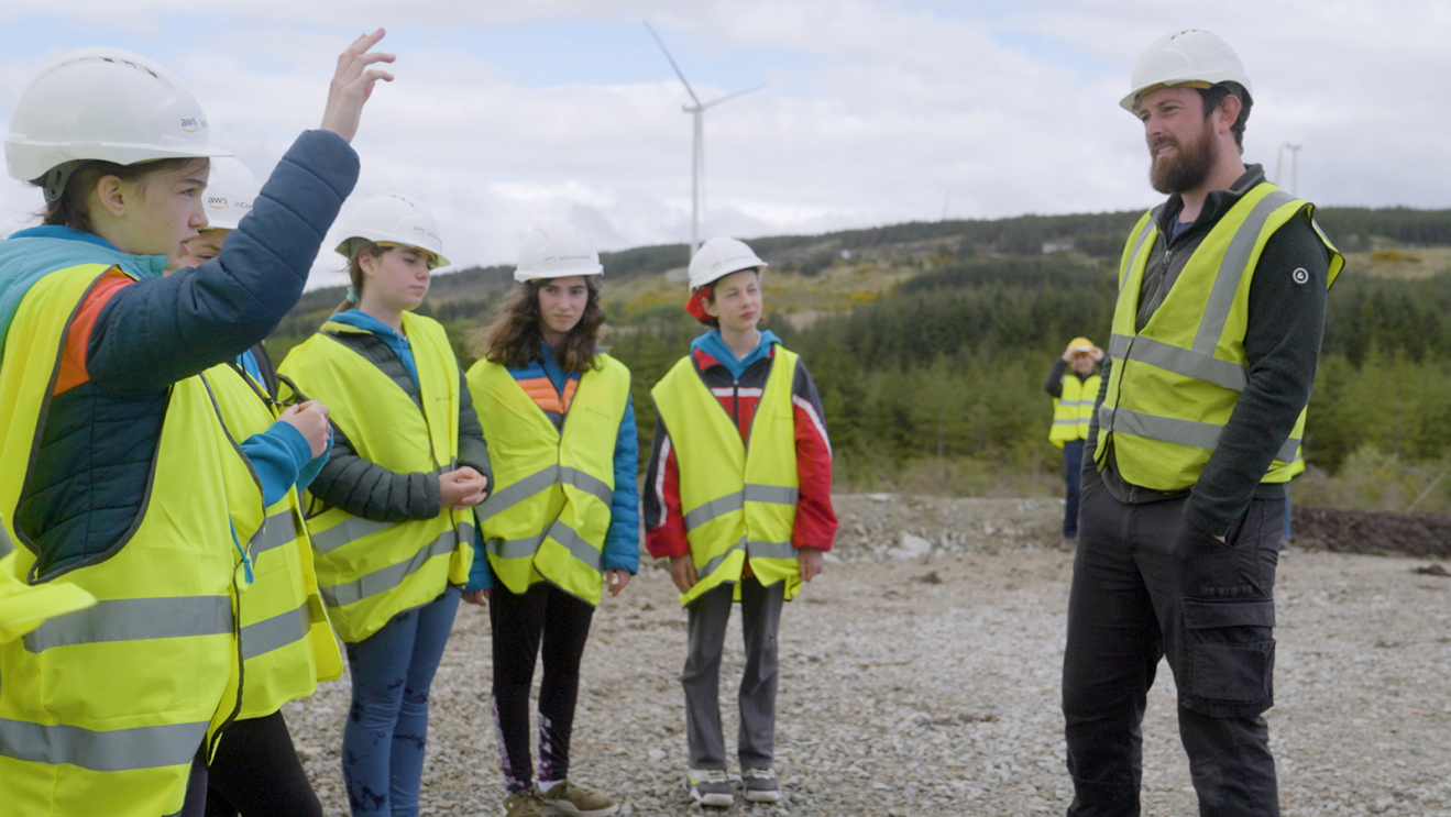 Uma foto de Gearoid TK, gerente de projetos de construção de parques eólicos, conversando com estudantes em um parque eólico da Amazon no Condado de Galway, Irlanda.