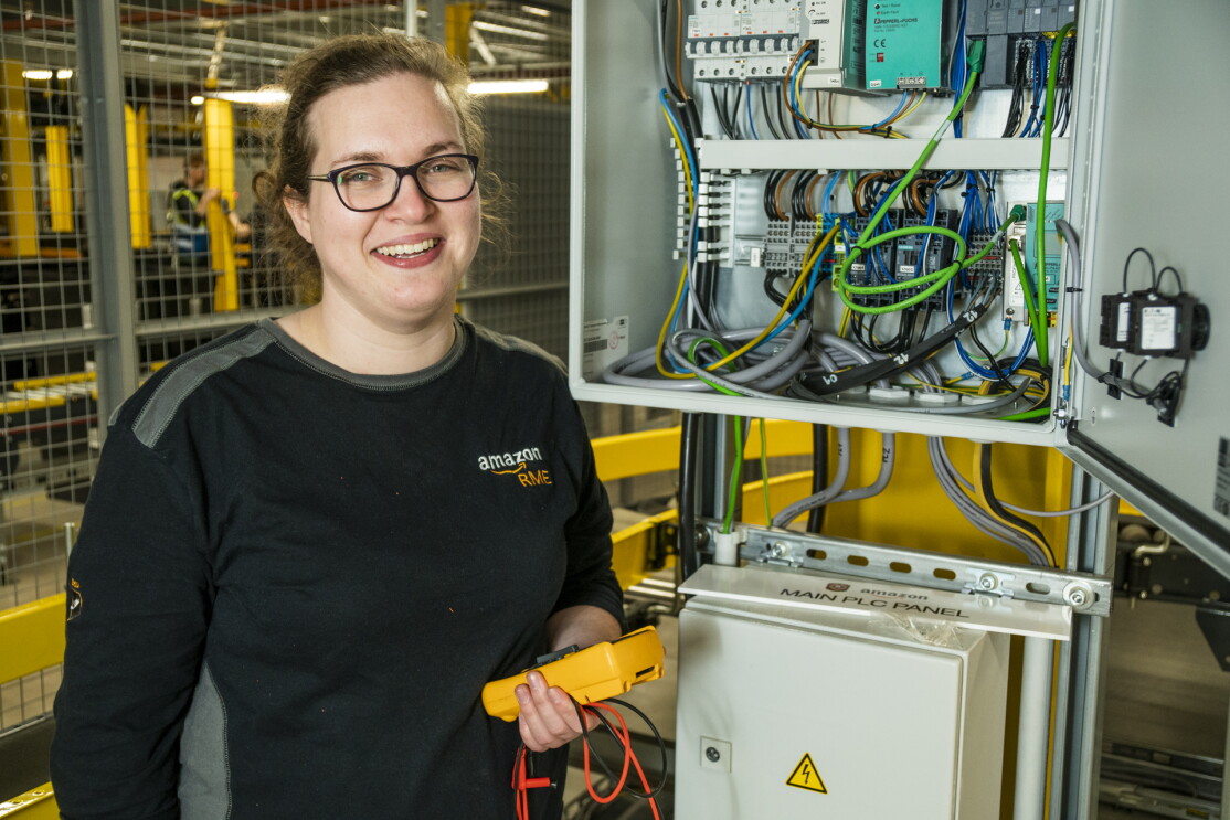 Nicola Elliott, automation engineering apprentice standing in front of an electrical unit. 