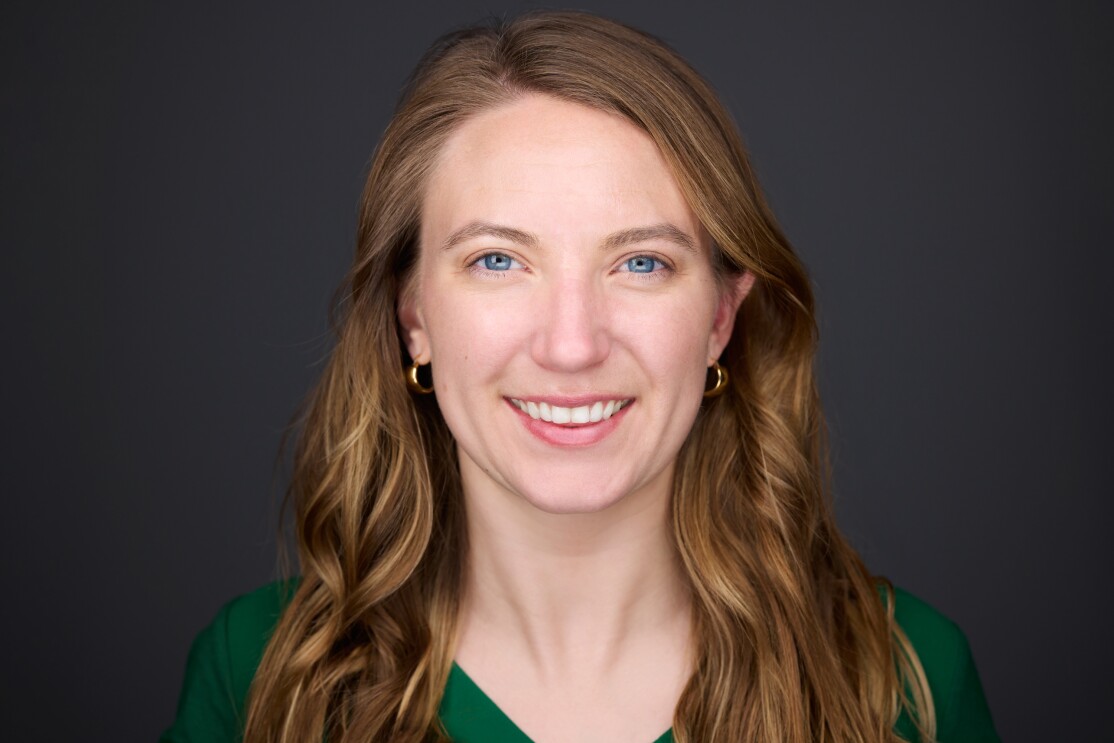 An image of a woman smiling for a headshot photo against a black background.