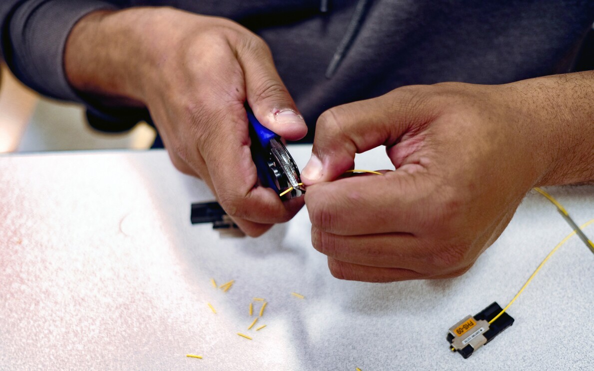 An image of a man's hands working on a piece of fiber optic cable.