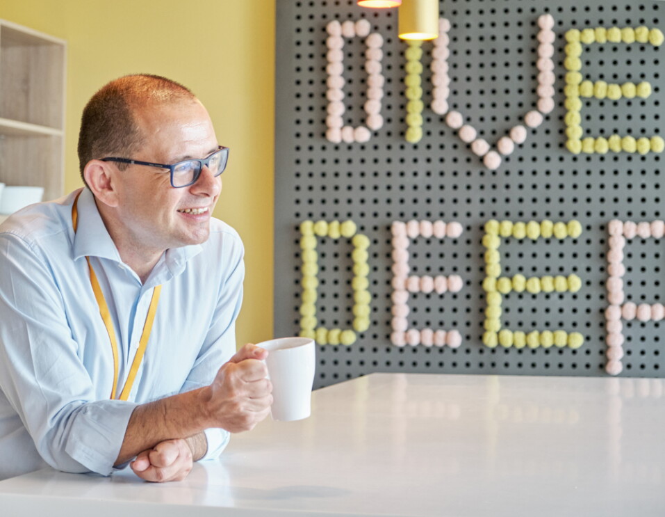 Federico Finzi, Legal Director di Amazon Italia e bar raiser, sorride e regge una tazza di caffé nella cucina dell'ufficio