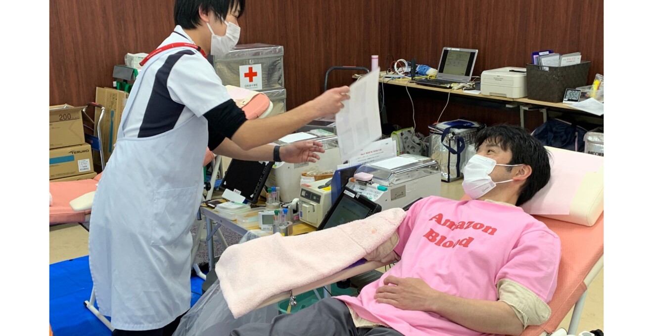 ベッドに横になって採血中の関さんと看護師さんの写真