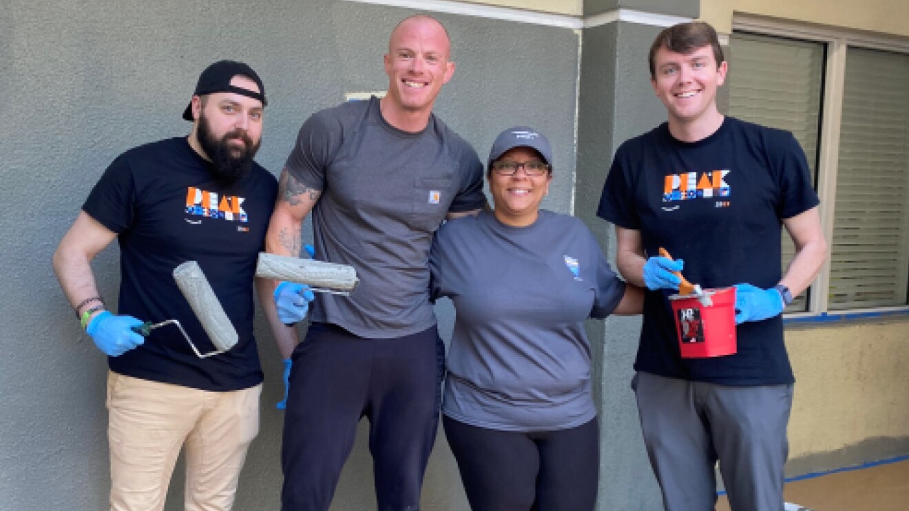 Josh stands alongside volunteers who pose for a pic while painting a home.