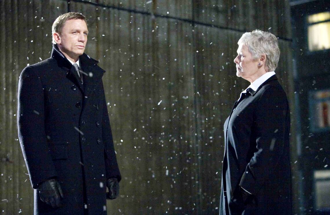 James Bond and M face each other during snowfall at night in a still from Quantum of Solace