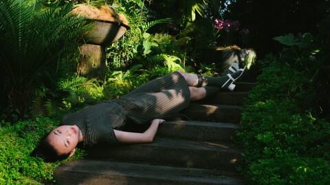 Model laying against stairs in a tropical setting