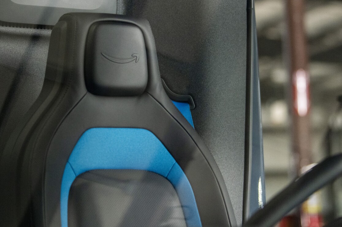 A steering wheel and vehicle seat bearing the Amazon smile logo.