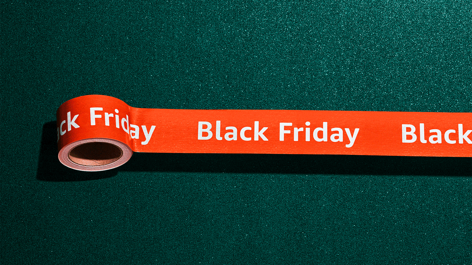 Bright red Black Friday packaging tape set on a green background.