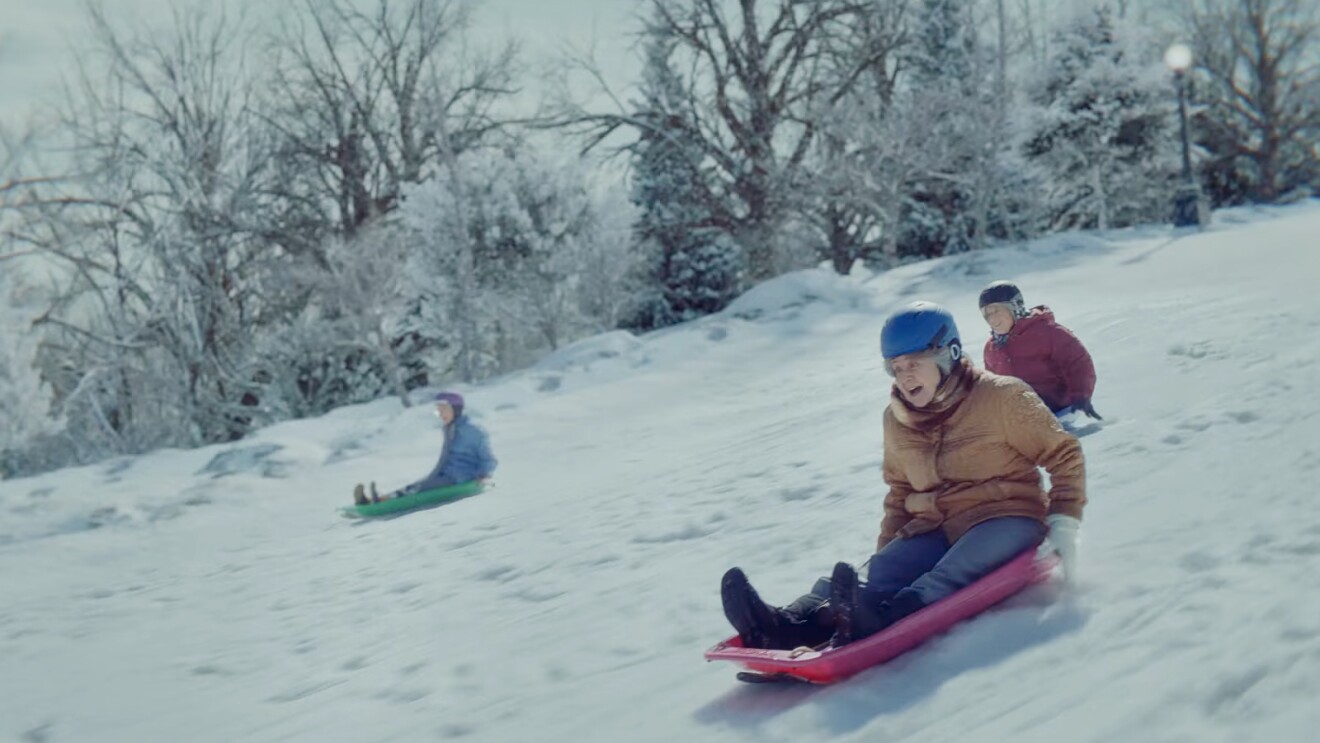 People sledding down snowy hill in winter landscape in Amazon Christmas ad