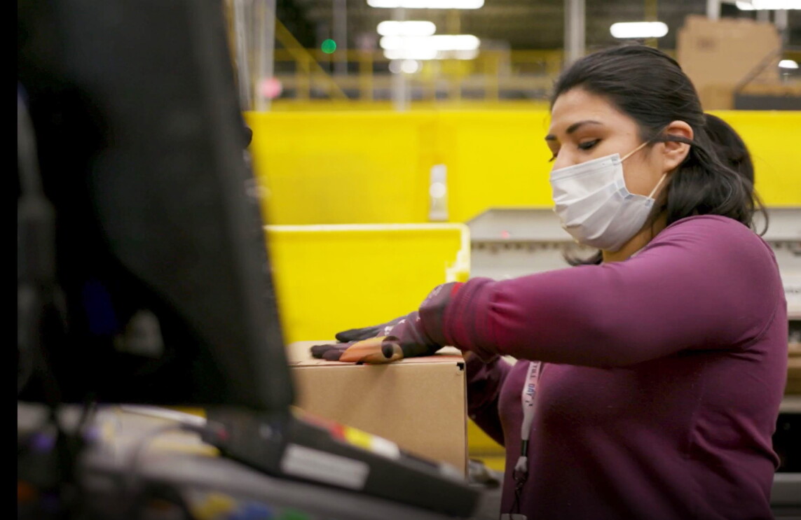 Amazon employee performing work duties while wearing a mask, during COVID-19 pandemic.