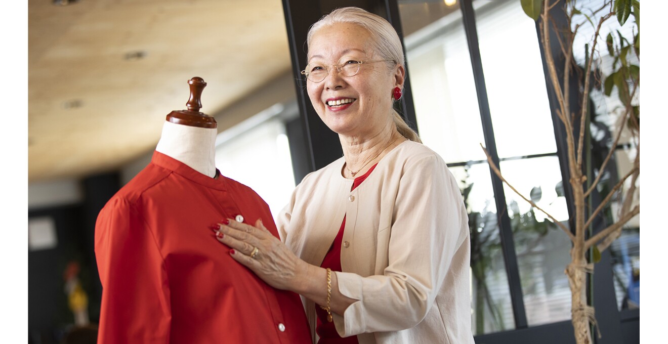 ブランドの商品を手に誇らしげなケイコさんの写真