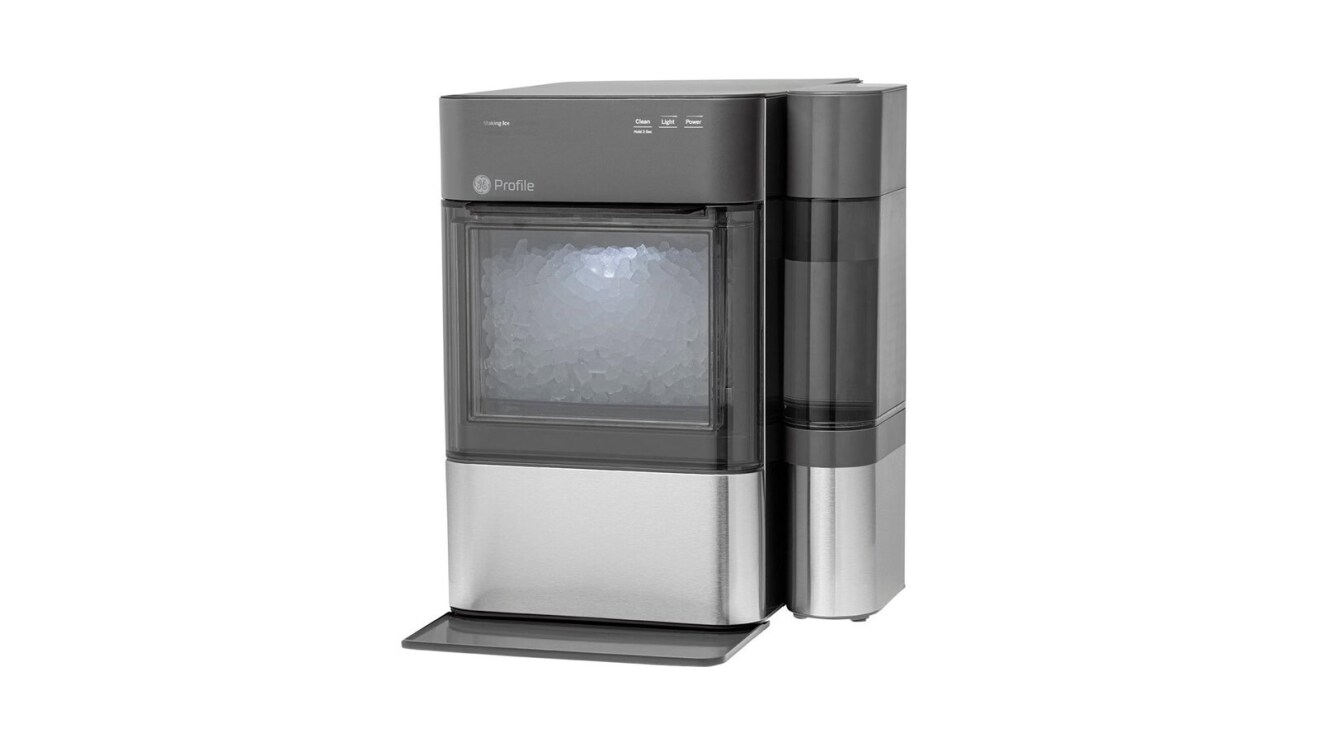 An image of the GE nugget ice maker. It is a relatively small ice maker with dark gray and stainless steel features. It has an opaque opening on the front where you can see the ice being made.