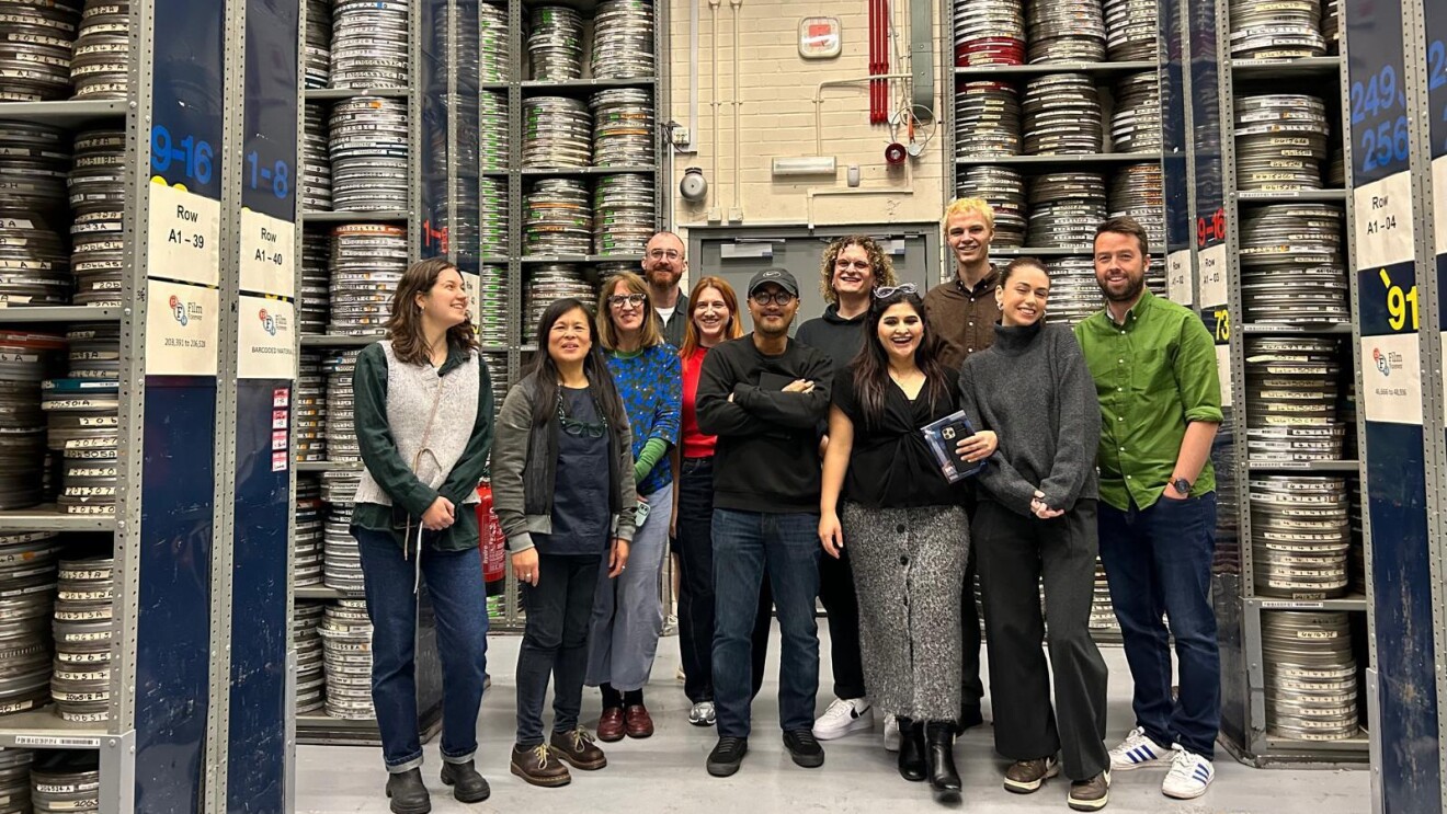 Group photo of diverse team in front of film reel storage shelves