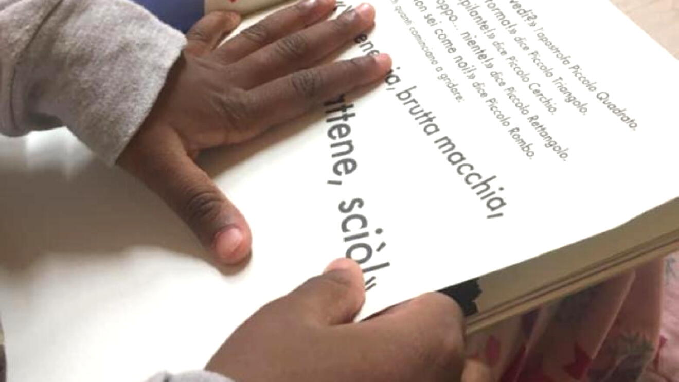 Primo piano delle mani di un bambino che reggono e sfogliano un libro