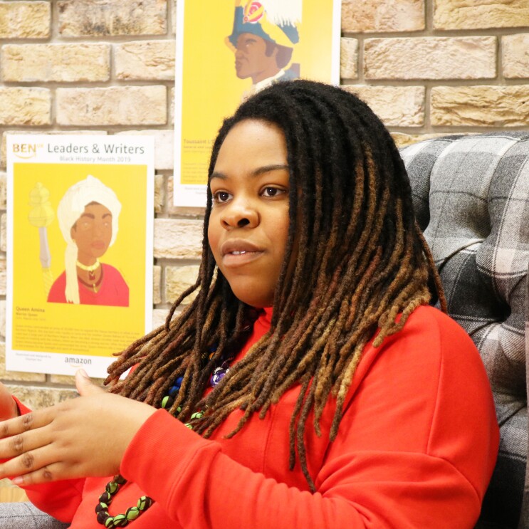 Artist Onyinye Iwu discussing Black History Month in front of her artwork