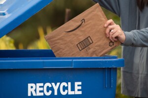 An image of a person putting an Amazon package in the recycle bin.