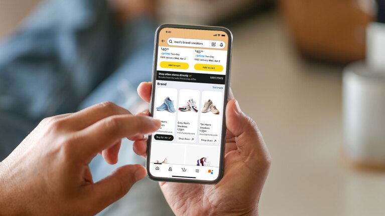 Hands holding smartphone displaying men's sneaker on Amazon website