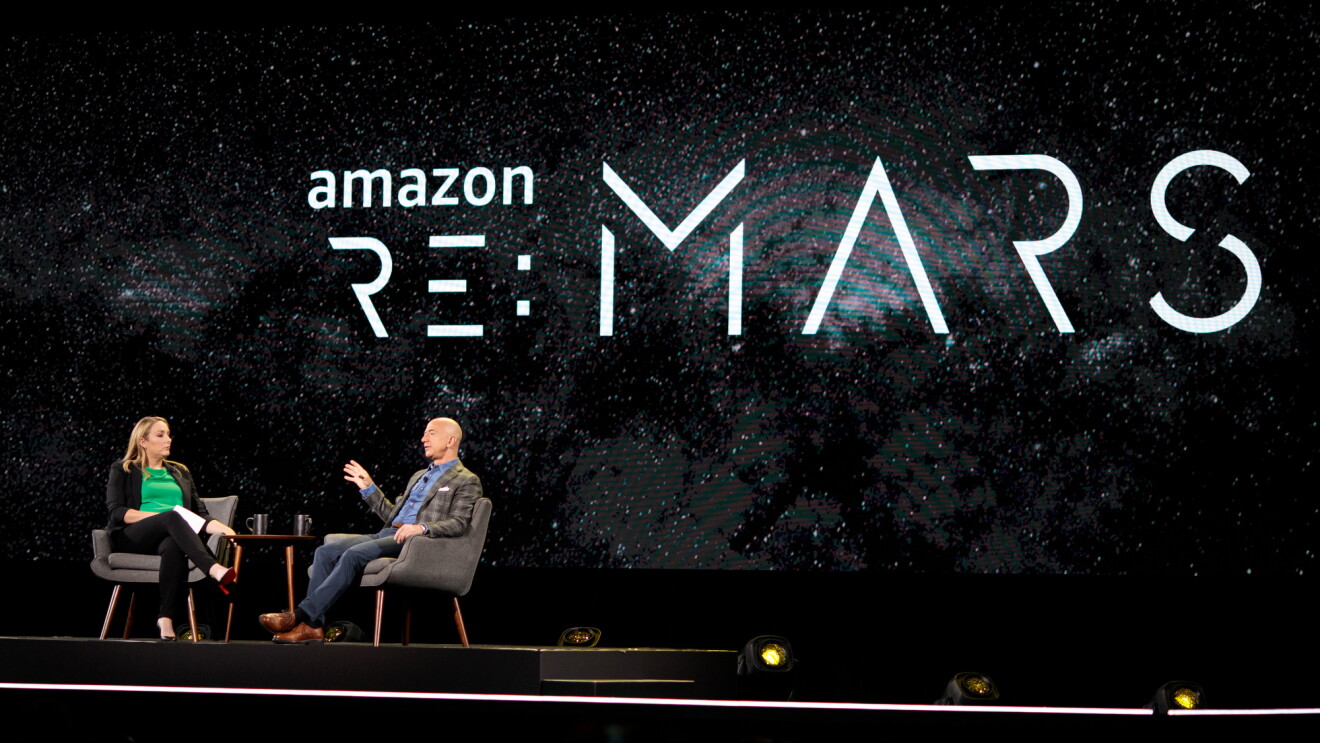 Jeff Bezos and Jenny Freshwater sit in chairs on stage at re:MARS 2019, for a fireside chat.