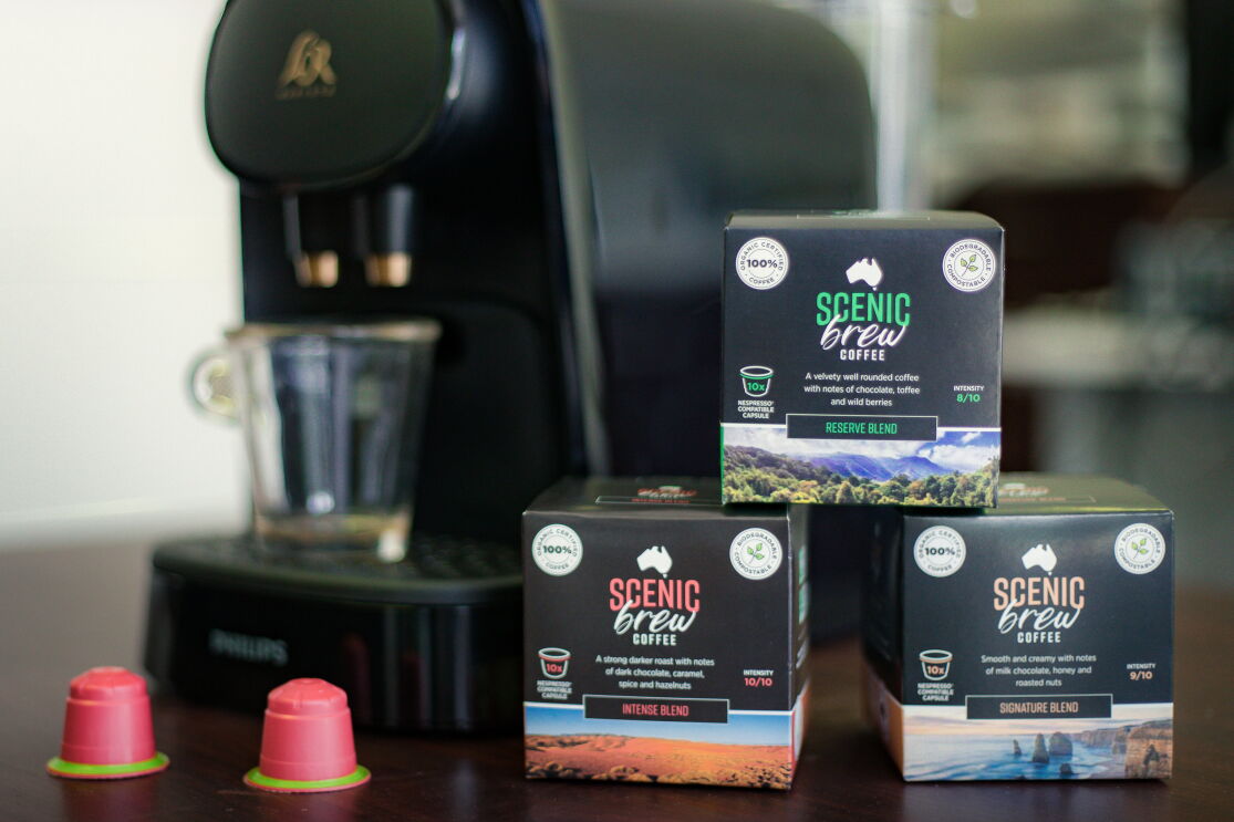 Three boxes of scenic brew coffee in front of an espresso maker