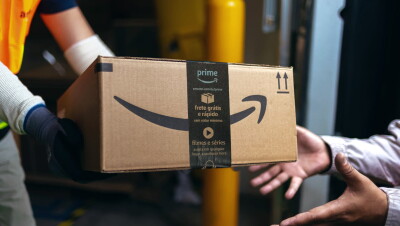 Uma pessoa entrega uma caixa da Amazon Prime. Outra pessoa recebe a embalagem