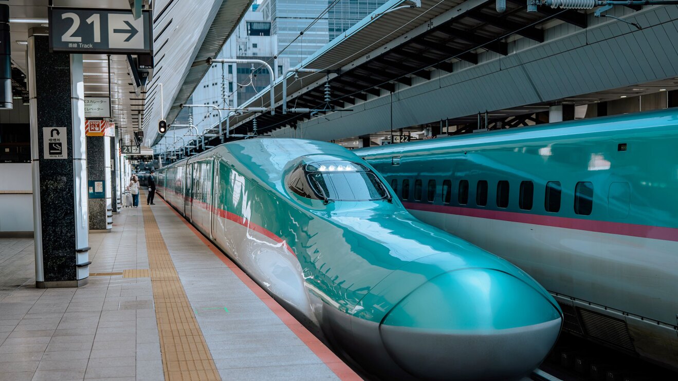ホームに停車中の新幹線の先頭部分。奥の線路にも同じカラーリングの新幹線。