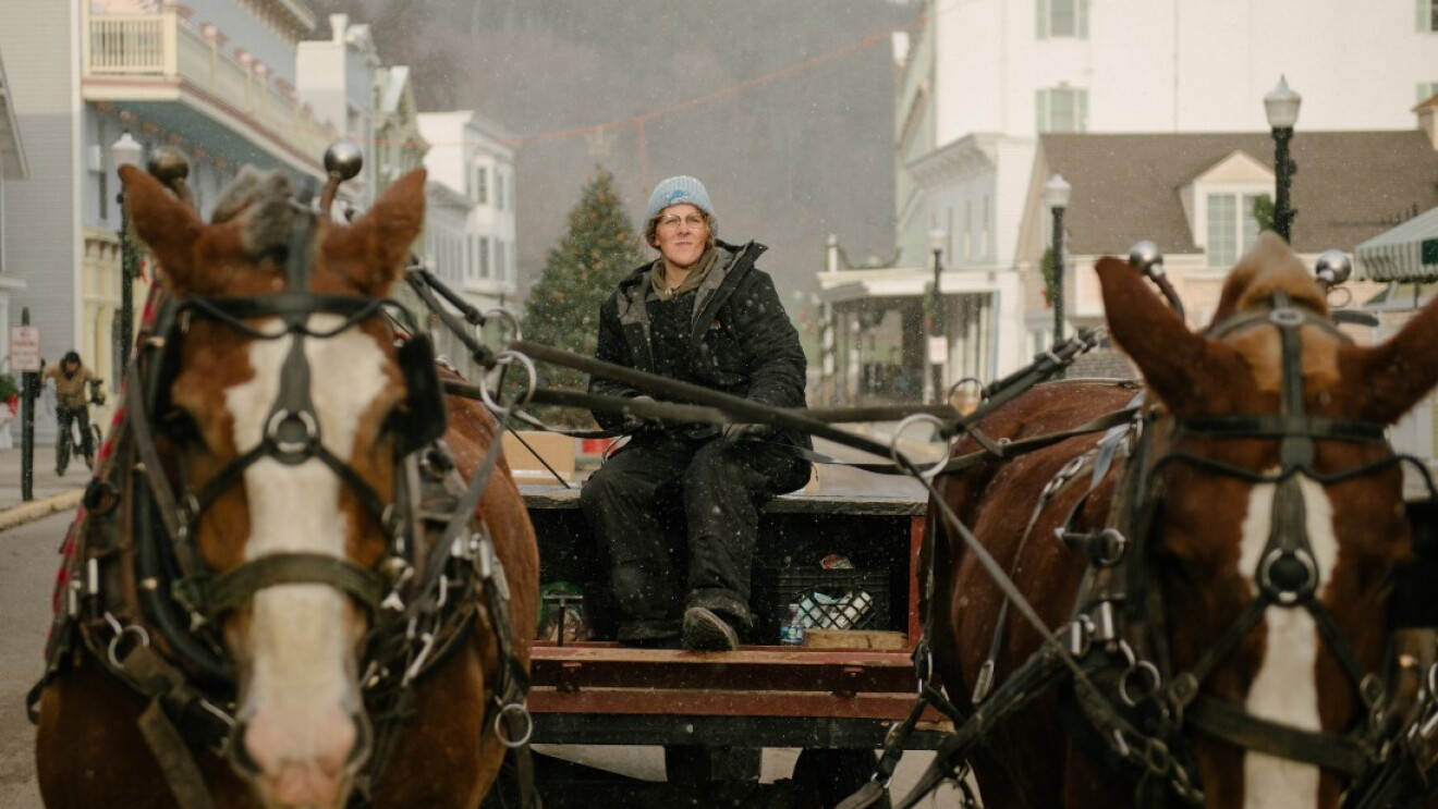 A woman rides a horse and dray carriage to deliver Amazon packages to the people that live on Mackinac Island.