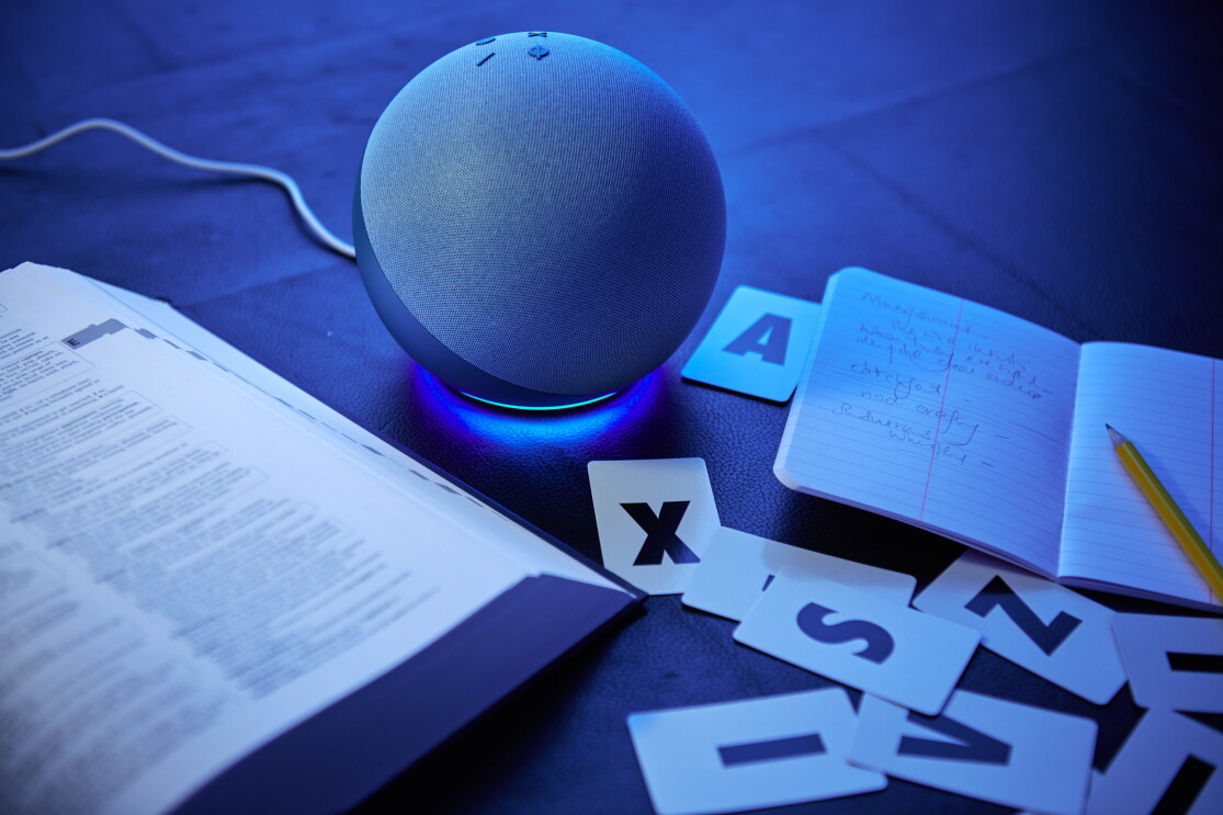An Amazon Echo on a library table next to a dictionary and letter cards.