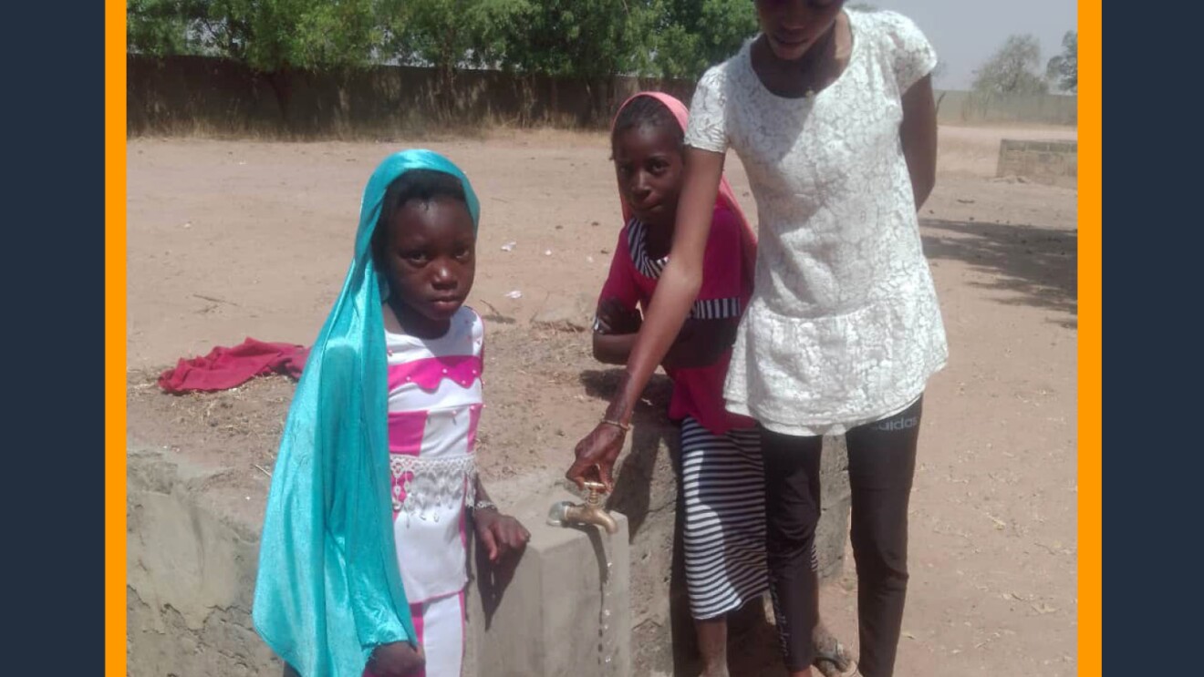 A photo of three students standing next to an outdoor water faucet at a school in a village of Medina Thiamene in Senegal. 