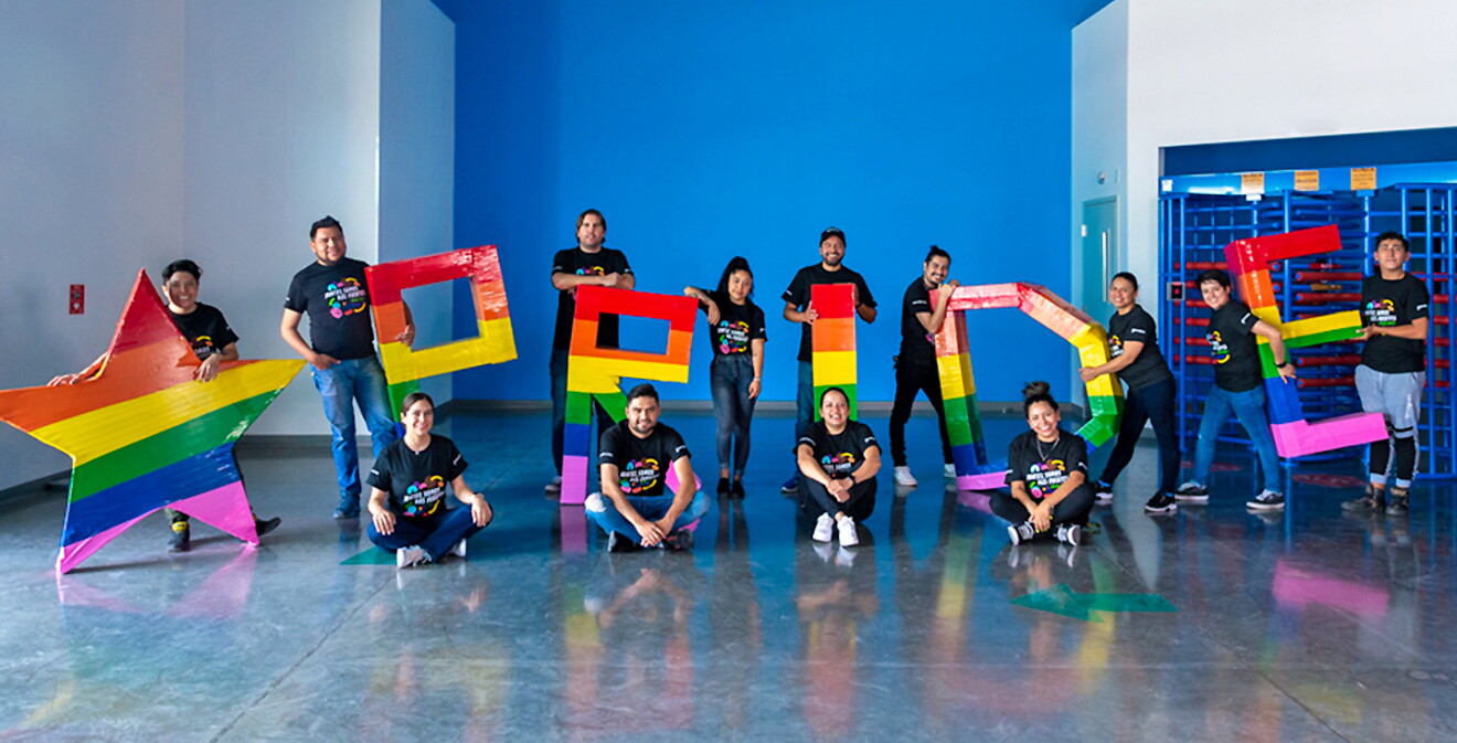 Una imagen de varios empleados de Amazon sosteniendo palabras coloridas que leen "Pride". 