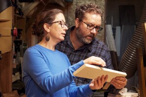 A man and a woman look at a piece of wood together.