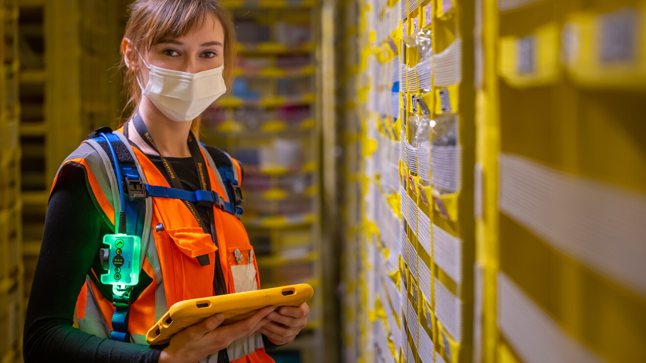 Eine junge Frau mit Sicherheitsweste in einem Amazon Logistikzentrum.