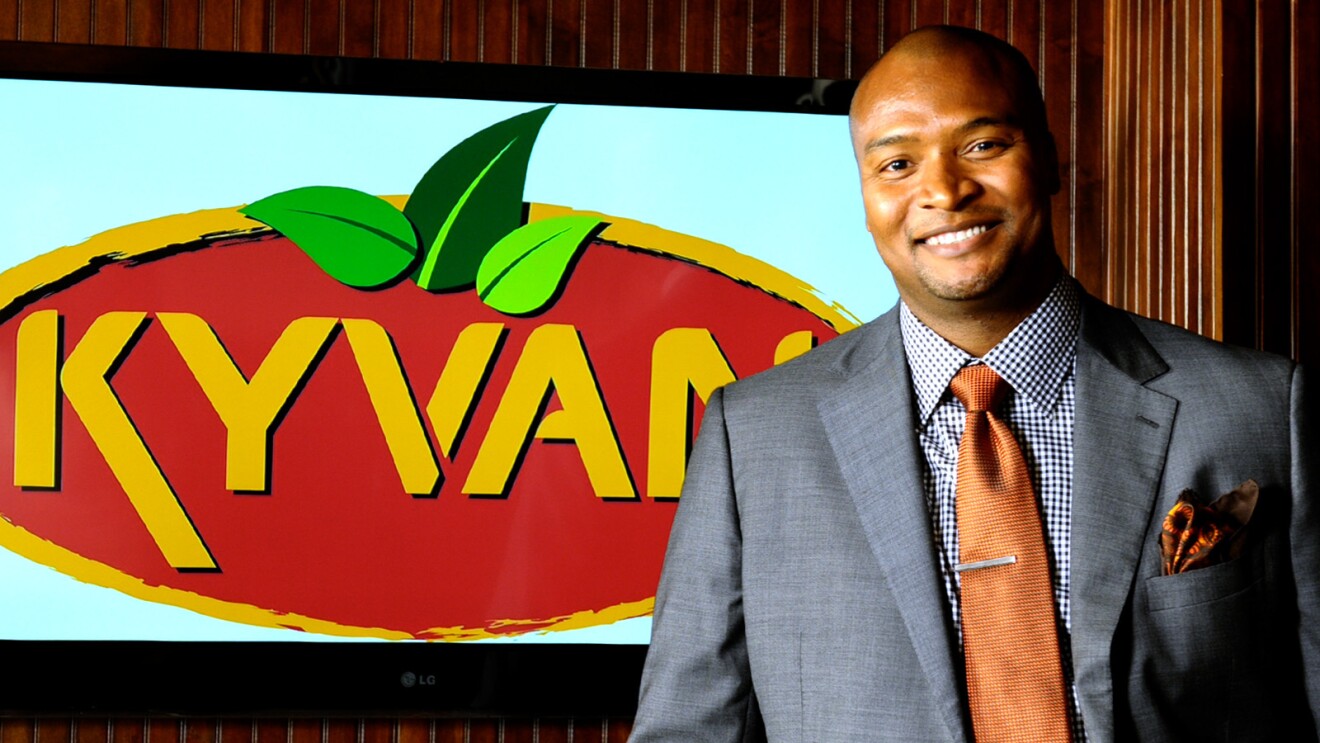 雷吉·凯利的照片,老板KYVAN食物,站在前面的一个KYVAN食物的迹象。