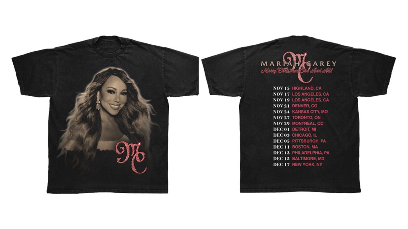 A black shirt with a large image of Mariah Carey on the front. Below her image is pink lettering that says "MC." On the back is a list of all of the stops of her holiday tour and lettering above the list that says "MC"