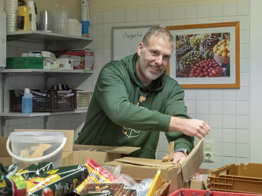 Ein Mitarbeiter im grünen Hoodie sortiert Waren