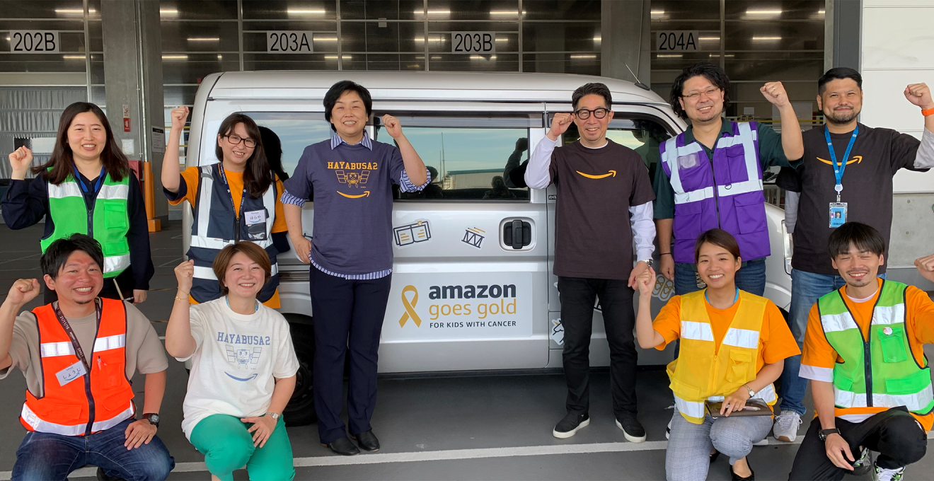 「amazon goes gold」と描かれデコレーションされた配送者を囲む社員たち