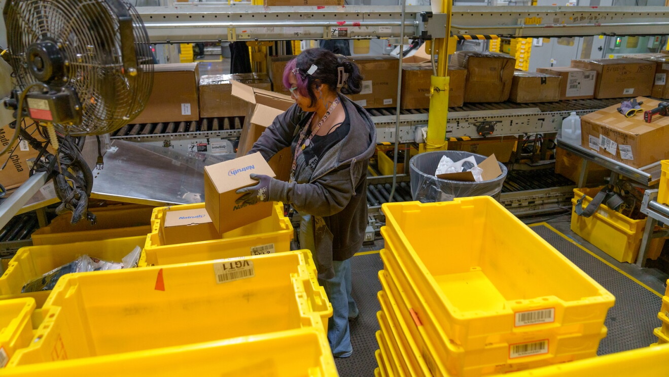 An Amazon associate loads boxes into bins at Amazon BDL4.