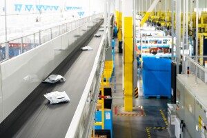 Amazon packages on a conveyor belt in a fulfillment center.