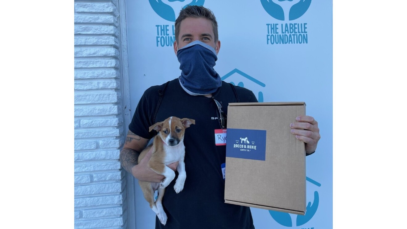 Owners hold their new adopted puppy and a Rocco & Roxie box.