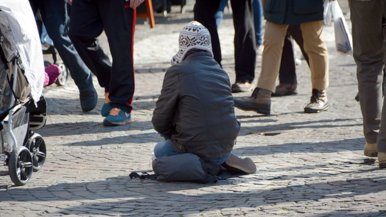 obdachloses kind sitzt auf der Straße, Menschen laufen drumherum