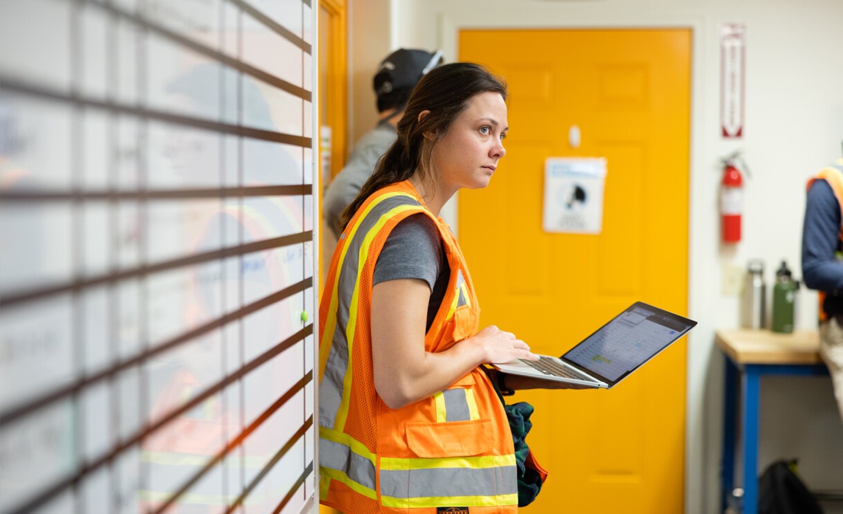 Images of Amazon employees wearing orange safety vests work on drones.