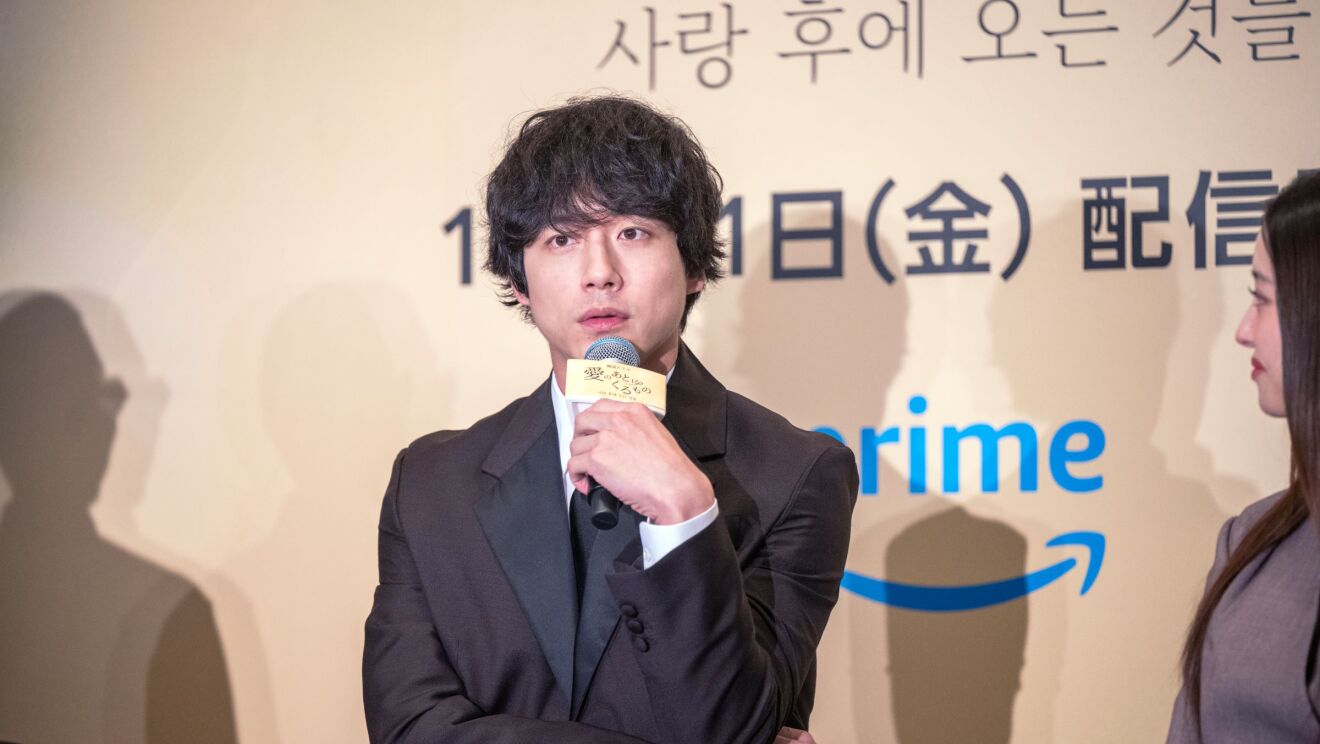 マイクを左手に持っている男性が前に向かって話している