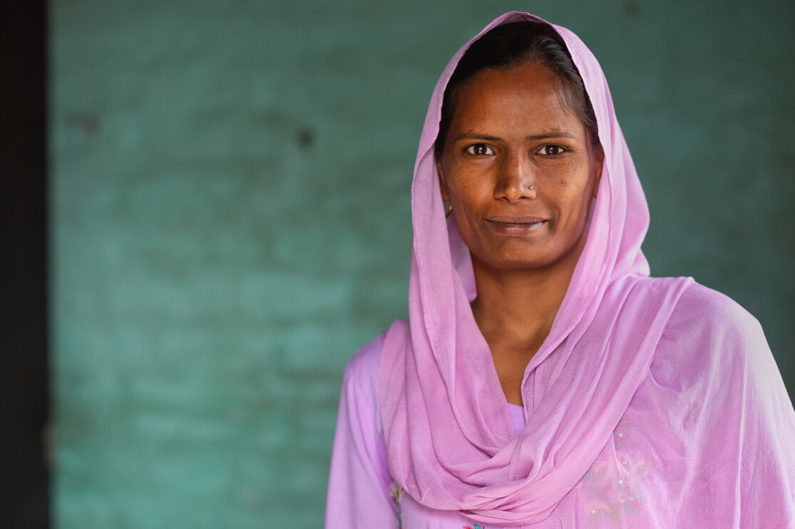 Portrait of a woman wearing a pink top and head scarf.