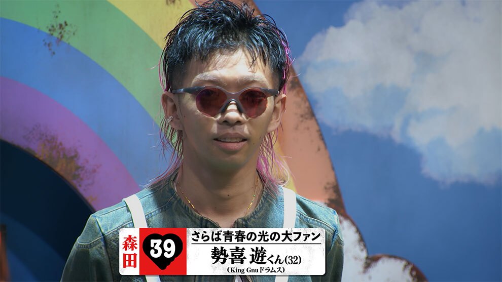 雲が描かれた青空の壁、虹色だが表面があれたアーチを背景に、サングラスをかけた人物の上半身。下部に「さらば青春の光の大ファン」、「勢喜 遊くん(32) (King Gnuドラムス)」の表示がある。