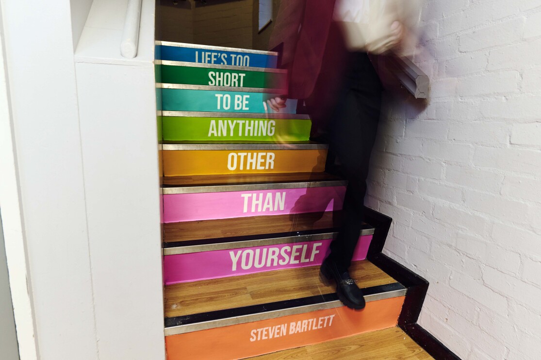 A student walks down the steps with a Steven Bartlett quote printed