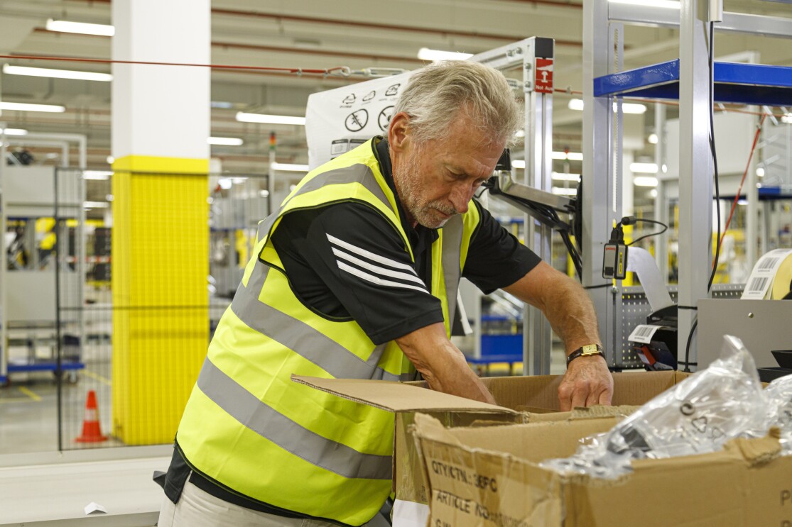 Ein Herr mit grauen Haaren und Sicherheitsweste beim Packen